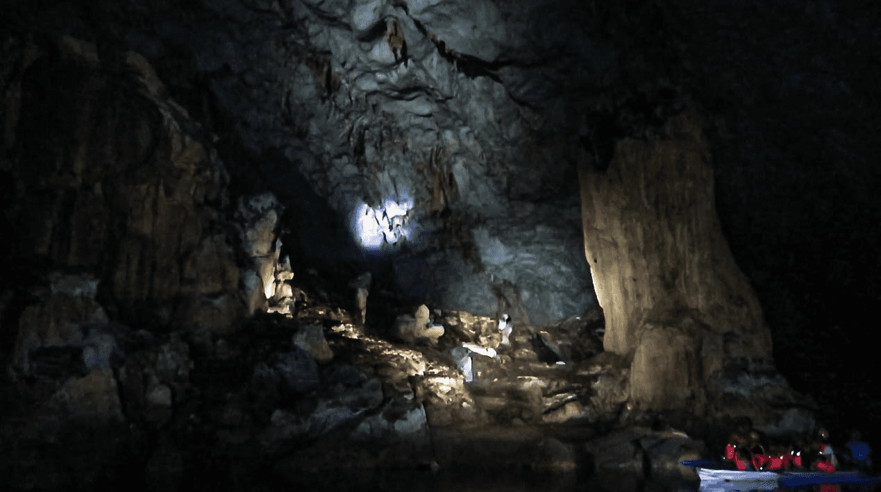 tourists in boat with helmets in puerto princesa underground river in palawan philippines with rock formations and stalagmites and stalagtites